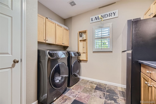 clothes washing area featuring washer and dryer and cabinets