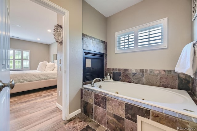 bathroom with hardwood / wood-style flooring and tiled bath