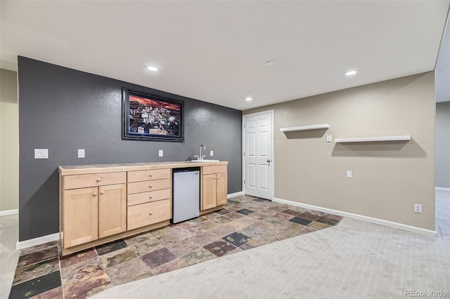 kitchen featuring light brown cabinetry, sink, and refrigerator