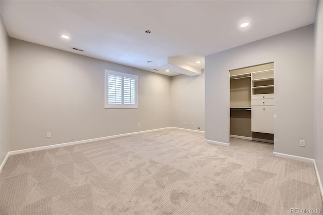 interior space with a walk in closet and light colored carpet