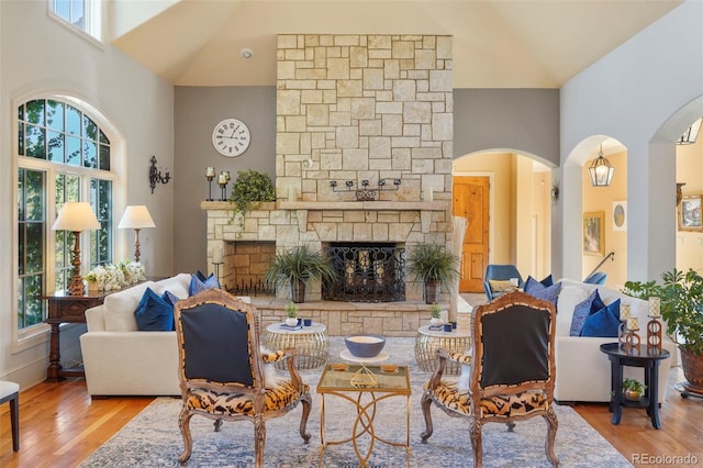 1975 Fox Mountain Pt, Colorado Springs, CO 80906 - living room featuring a stone fireplace, high vaulted ceiling, wood finished floors, and arched walkways