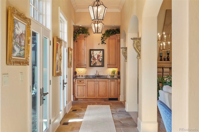 1975 Fox Mountain Pt, Colorado Springs, CO 80906 - bar with ornamental molding, arched walkways, a sink, hanging light fixtures, and a notable chandelier