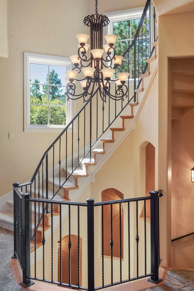 1975 Fox Mountain Pt, Colorado Springs, CO 80906 - staircase featuring a notable chandelier and arched walkways