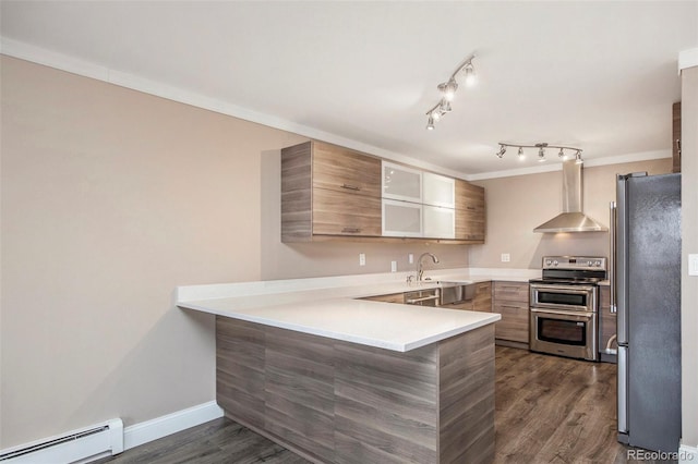 kitchen with appliances with stainless steel finishes, ornamental molding, a peninsula, wall chimney range hood, and a baseboard heating unit