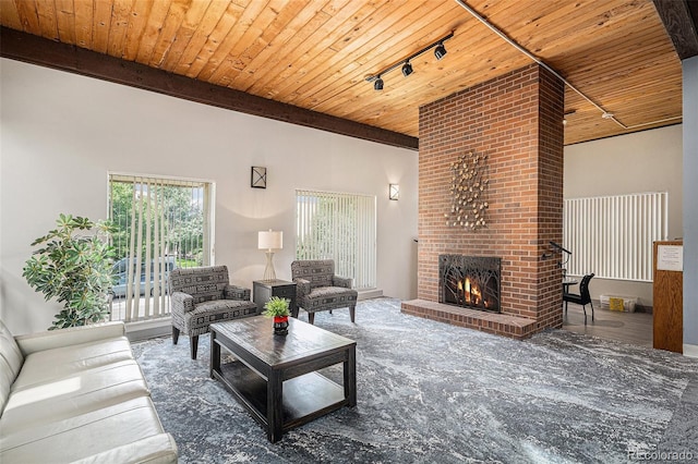 living room featuring beam ceiling, a brick fireplace, wood ceiling, and track lighting