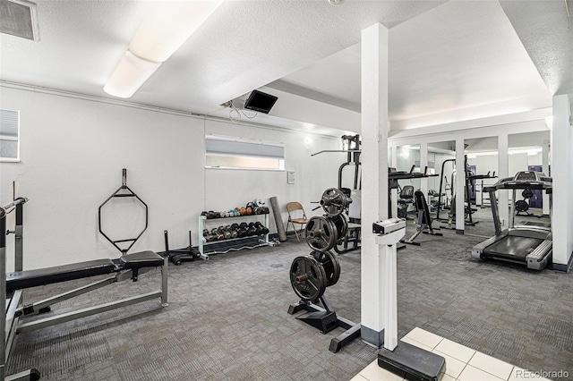 workout area featuring carpet, visible vents, and a textured ceiling