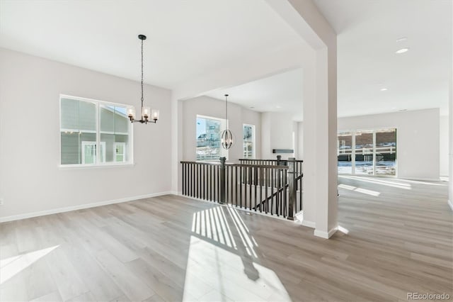 unfurnished room featuring light wood-type flooring and a notable chandelier