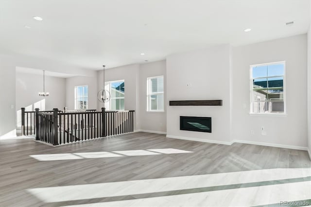 unfurnished living room featuring light hardwood / wood-style flooring and a notable chandelier