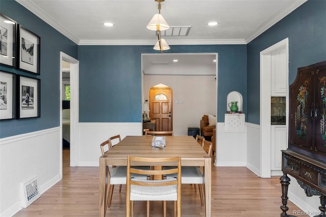 1265 S Elizabeth St, Denver, CO 80210 - dining room with arched walkways, light wood finished floors, crown molding, a wainscoted wall, and recessed lighting