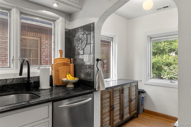 1265 S Elizabeth St, Denver, CO 80210 - kitchen with stainless steel dishwasher, arched walkways, light wood-style flooring, dark stone counters, and white cabinets