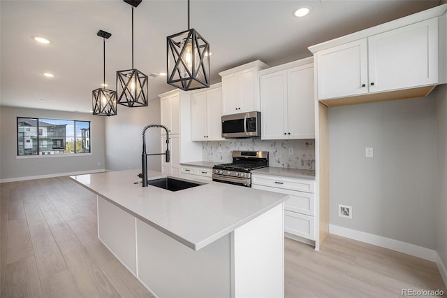 kitchen with an island with sink, a sink, stainless steel appliances, white cabinetry, and tasteful backsplash