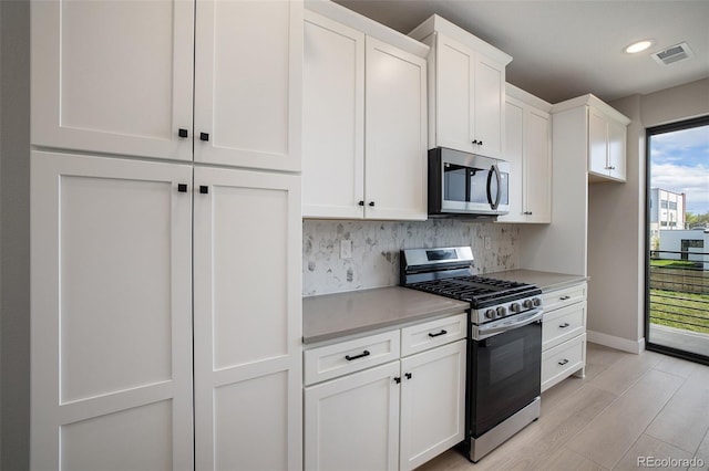 kitchen with visible vents, light countertops, light wood-style flooring, appliances with stainless steel finishes, and white cabinetry