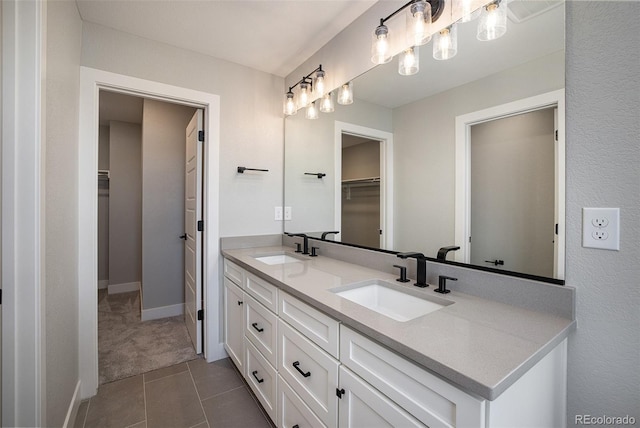 bathroom with double vanity, tile patterned floors, a walk in closet, and a sink