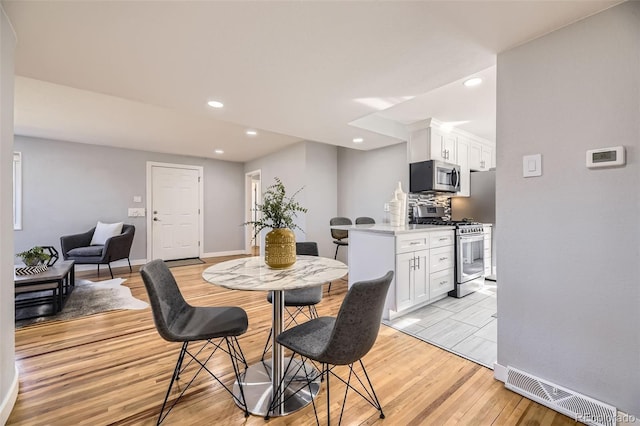 dining room with recessed lighting, visible vents, light wood-style flooring, and baseboards