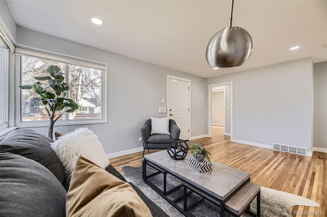 living area with light wood-type flooring, baseboards, visible vents, and recessed lighting