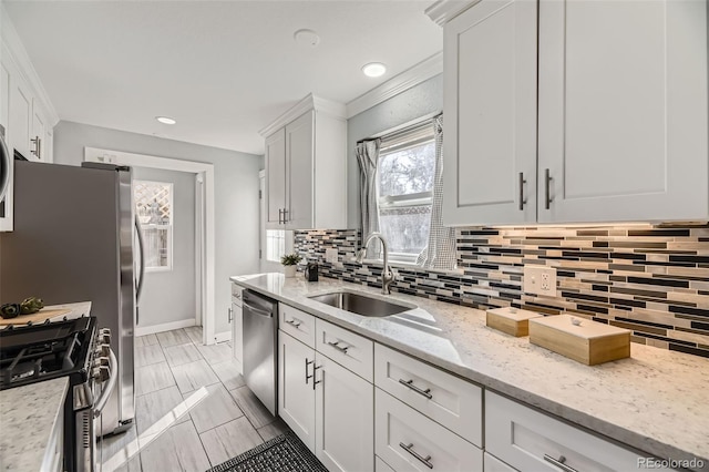 kitchen featuring appliances with stainless steel finishes, white cabinetry, a sink, and backsplash