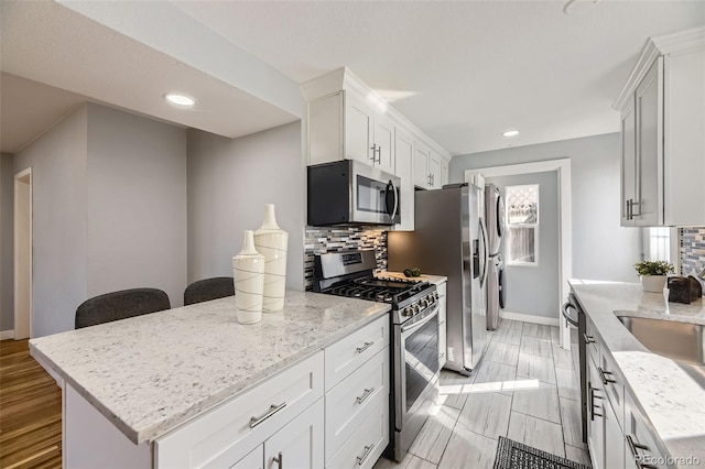 kitchen with light stone counters, tasteful backsplash, recessed lighting, appliances with stainless steel finishes, and white cabinets