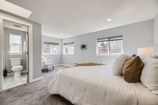 carpeted bedroom featuring connected bathroom, recessed lighting, a skylight, visible vents, and baseboards