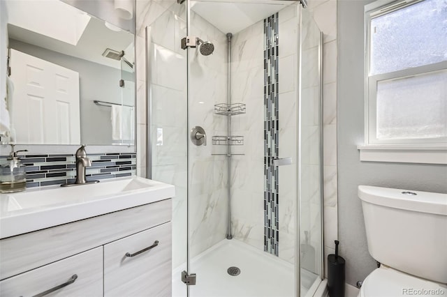 bathroom featuring vanity, a shower stall, toilet, and decorative backsplash