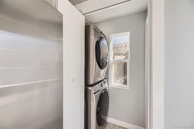 laundry area featuring stacked washer / drying machine, laundry area, and baseboards