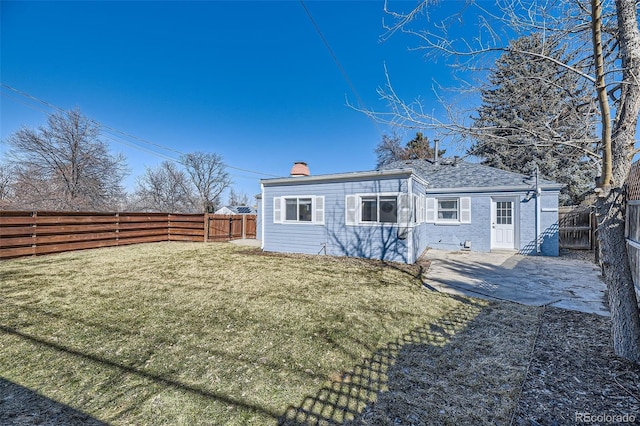 back of house with brick siding, a chimney, a lawn, a patio area, and a fenced backyard