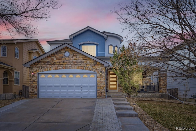 view of front of house featuring stone siding, a garage, concrete driveway, and stucco siding
