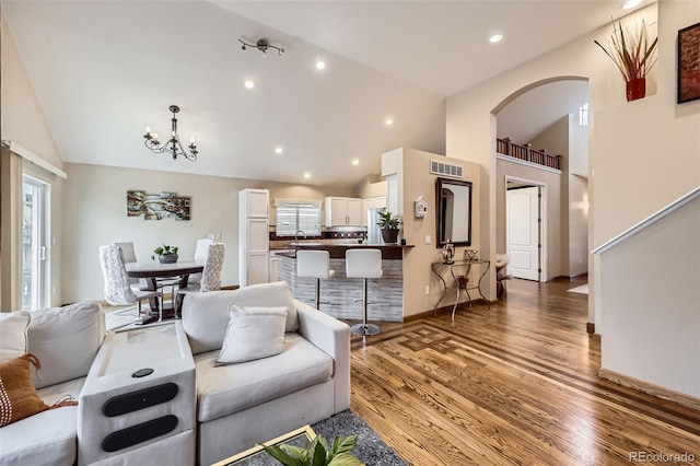 living room featuring recessed lighting, arched walkways, visible vents, a notable chandelier, and wood finished floors