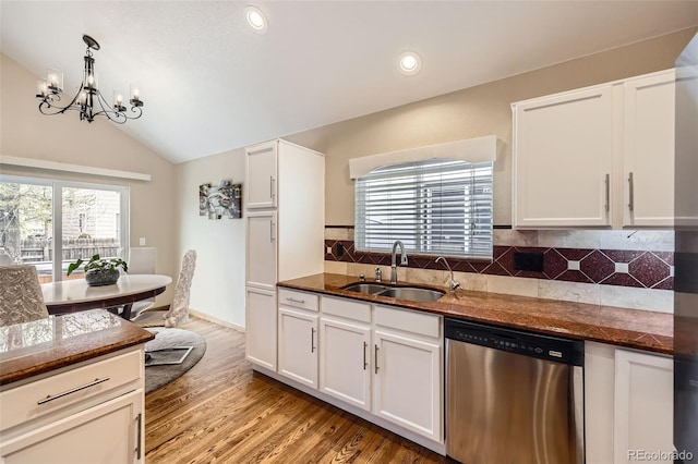 kitchen with vaulted ceiling, a notable chandelier, a sink, stainless steel dishwasher, and light wood-style flooring