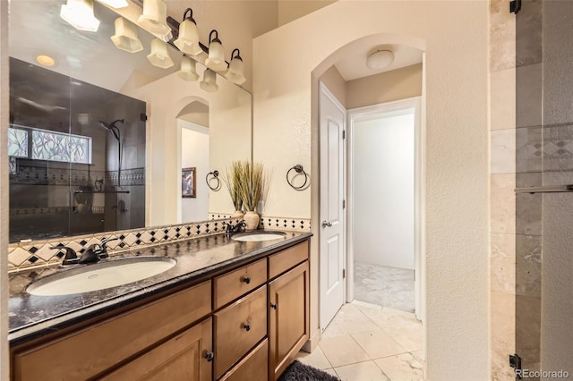 bathroom with double vanity, a sink, a tile shower, and tile patterned floors