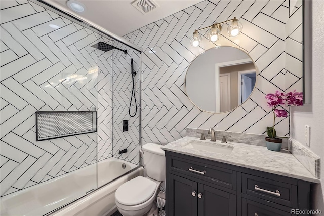 bathroom featuring toilet, vanity, enclosed tub / shower combo, and visible vents