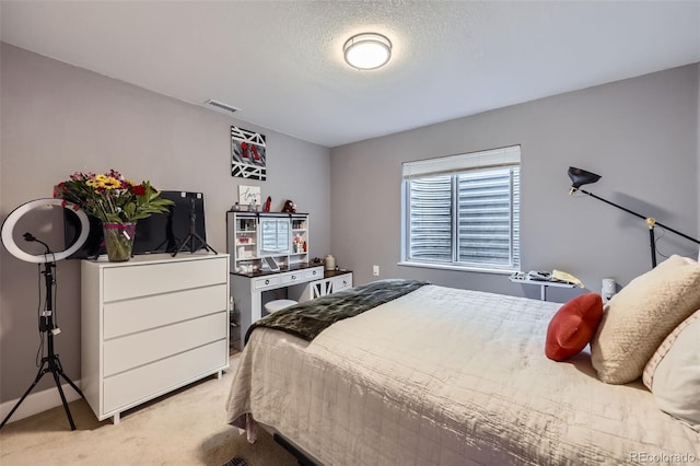 bedroom featuring light carpet, visible vents, and a textured ceiling