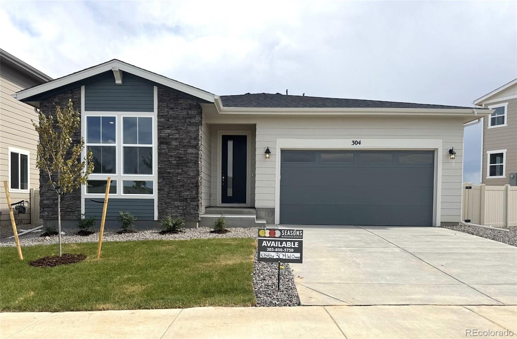 304 W Owen Ave, Keenesburg, CO 80643 - view of front of home featuring driveway, a front yard, and an attached garage