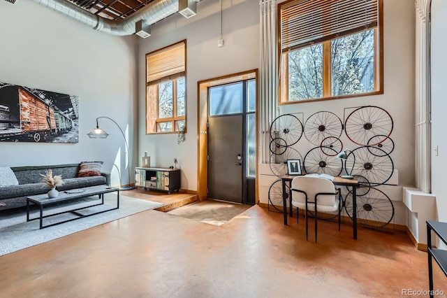 interior space featuring baseboards, a high ceiling, and concrete flooring