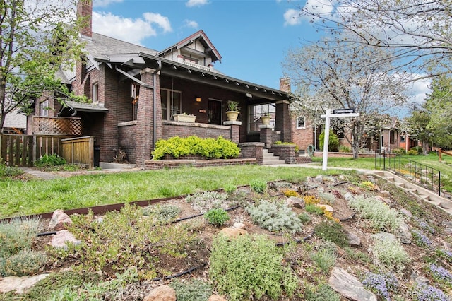 rear view of house with brick siding, fence, covered porch, and a chimney