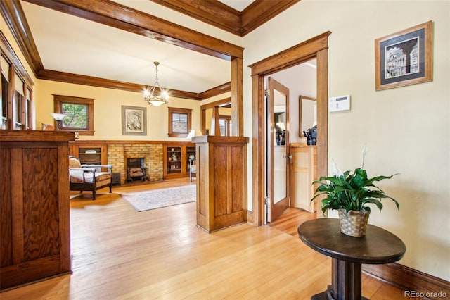 foyer featuring an inviting chandelier, ornamental molding, and light wood-style flooring