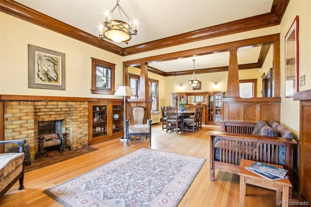 living area with ornamental molding, a fireplace, and wood finished floors