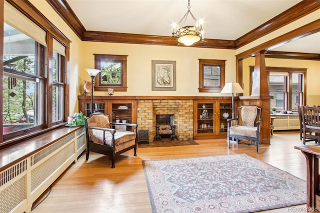 living area with crown molding, radiator, wood-type flooring, and a wealth of natural light
