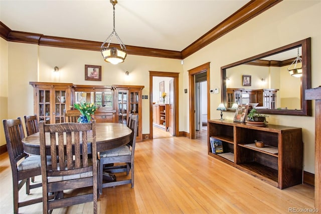 dining space with baseboards, ornamental molding, and light wood-style flooring