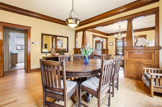 dining space featuring baseboards, ornamental molding, light wood finished floors, and an inviting chandelier