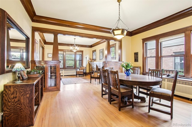 dining room with crown molding, light wood finished floors, and a chandelier