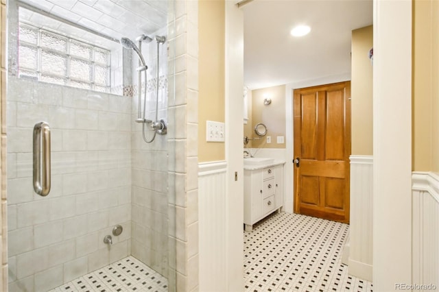 full bathroom with vanity, a wainscoted wall, and a shower stall