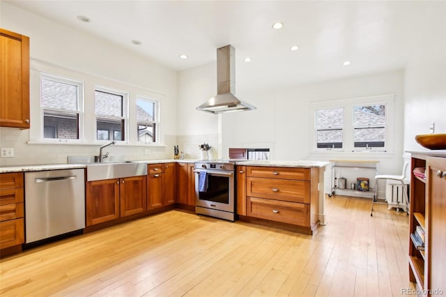 kitchen featuring island range hood, brown cabinets, tasteful backsplash, a sink, and appliances with stainless steel finishes