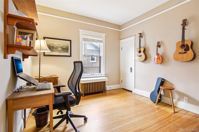 office area featuring radiator heating unit, baseboards, and light wood finished floors