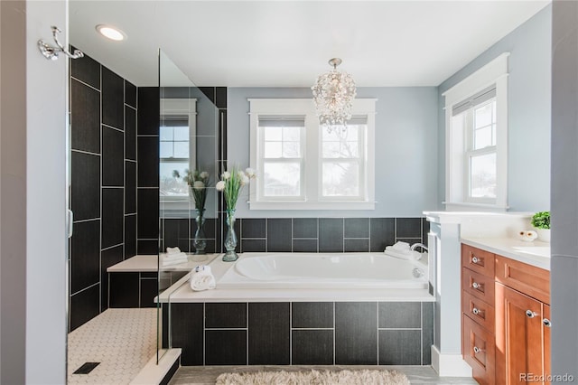 bathroom with plenty of natural light, shower with separate bathtub, vanity, and a chandelier