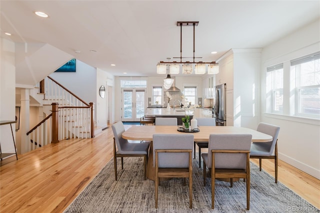 dining area with light wood-type flooring, sink, a wealth of natural light, and french doors