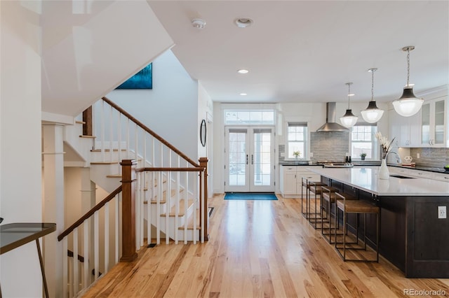 kitchen featuring backsplash, white cabinetry, french doors, and wall chimney range hood