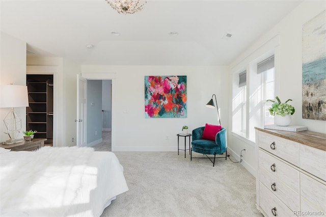 bedroom featuring light carpet and a walk in closet