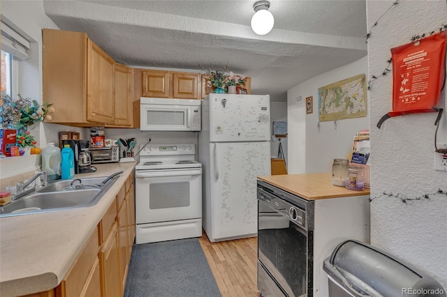 kitchen with sink, white appliances, light hardwood / wood-style floors, light brown cabinets, and a textured ceiling