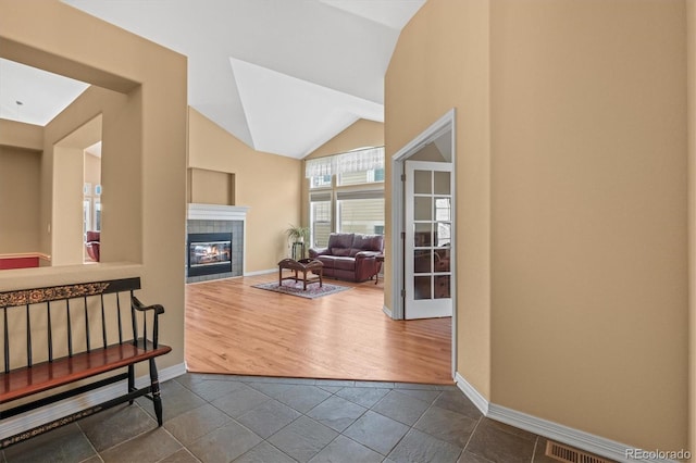 entryway featuring lofted ceiling, dark wood-style floors, baseboards, and a tiled fireplace