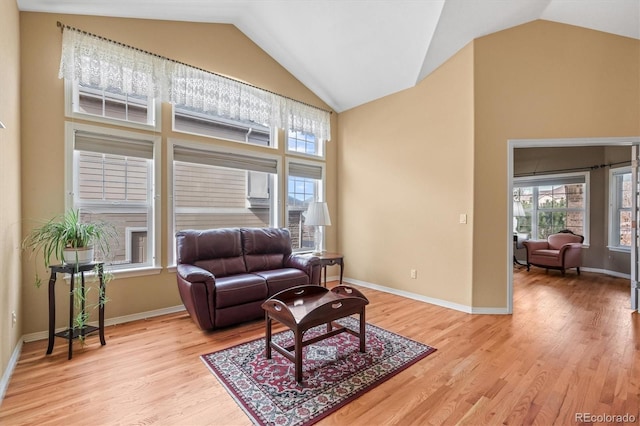 living room with high vaulted ceiling, baseboards, and light wood finished floors